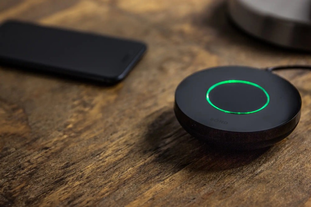 Bond Bridge smart home hub with glowing ring on a wooden surface
